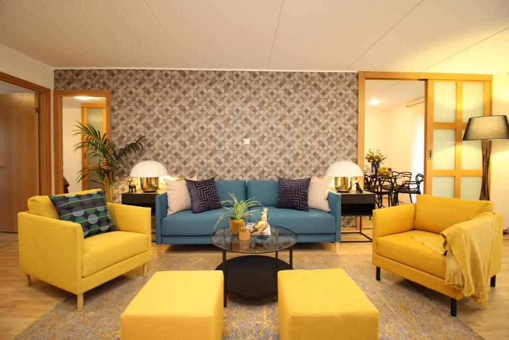 a living room with a blue couch and yellow chairs at Tallinn City Apartments Roosikrantsi in Tallinn