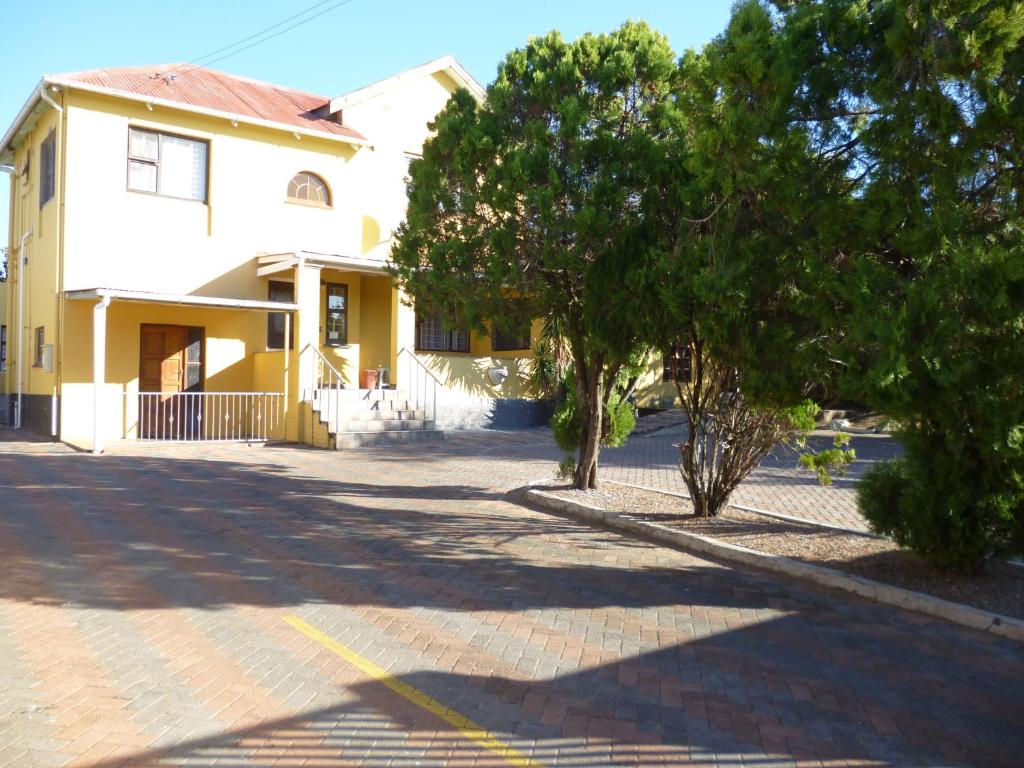 a yellow house with trees in front of a street at Royal Guest House in East London