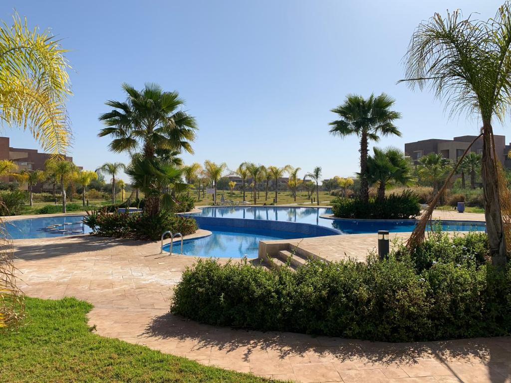 a resort with two pools and palm trees at Marrakech Prestigia Jade Golf Piscine in Marrakesh
