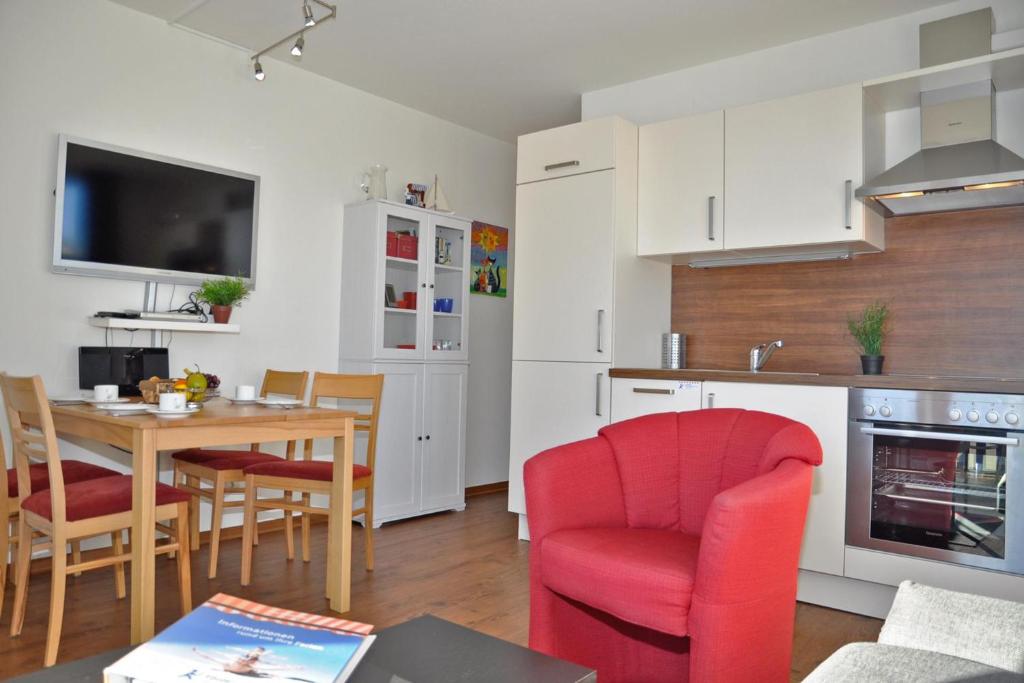 een keuken en eetkamer met een tafel en rode stoelen bij HR Nordwind in Laboe