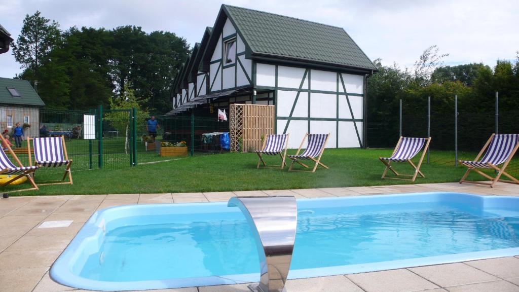 a swimming pool in a yard with chairs and a building at Ośrodek domków letniskowych Sztorm in Chłopy