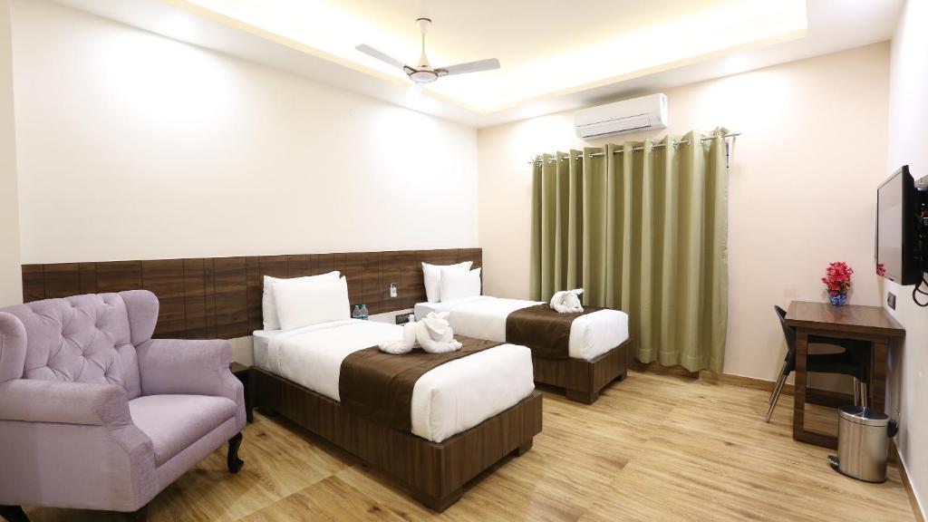 una camera d'albergo con due letti e una sedia di The Ventura Grand Hotel a Bangalore