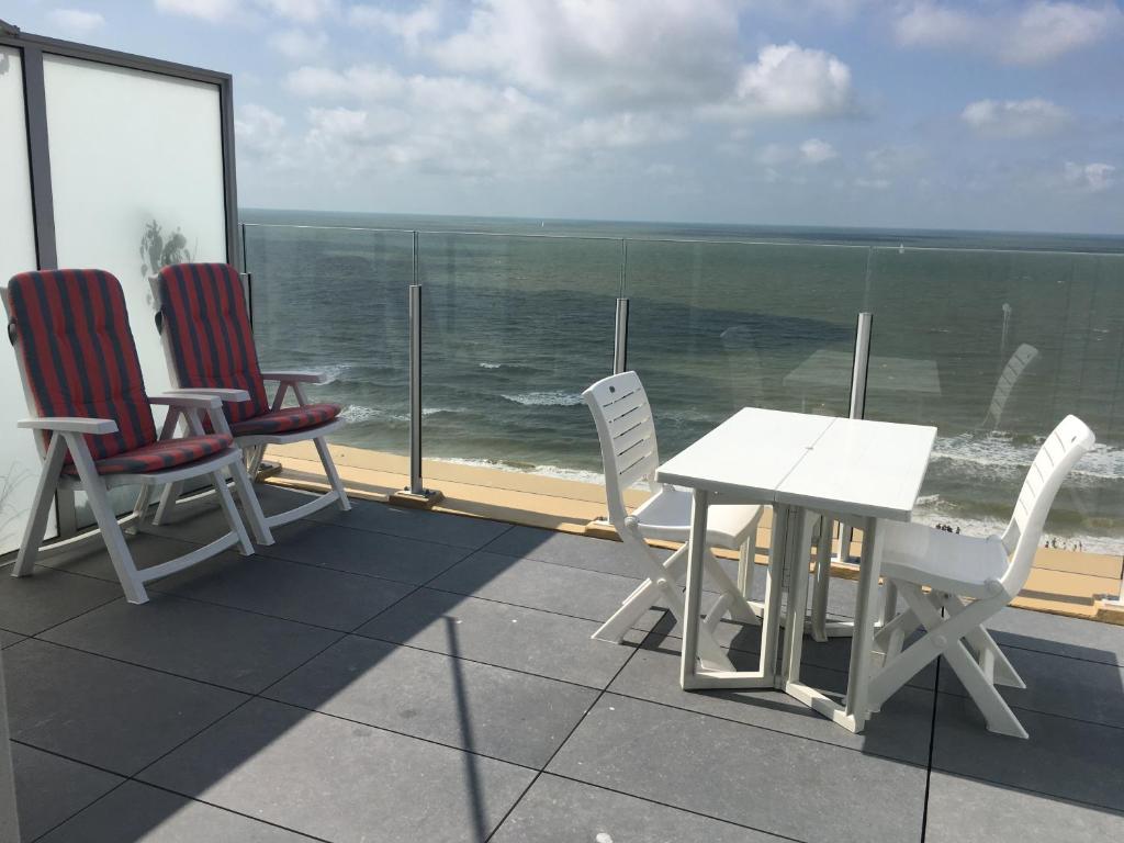 een tafel en stoelen op een balkon met uitzicht op de oceaan bij penthouse seafront in Oostende