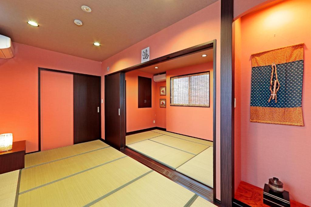 a hallway with orange walls and a game room at Guest House Ochakare in Kanazawa
