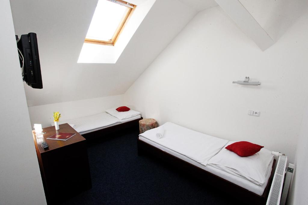 two beds in a small room with a window at Hotel Širák in Most