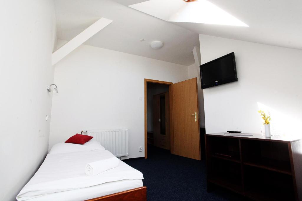 a bedroom with a bed and a tv on the wall at Hotel Širák in Most