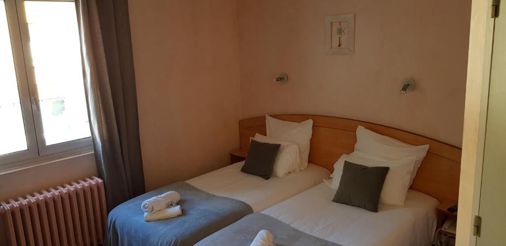 two twin beds in a room with a window at Hôtel Terminus in Luz-Saint-Sauveur