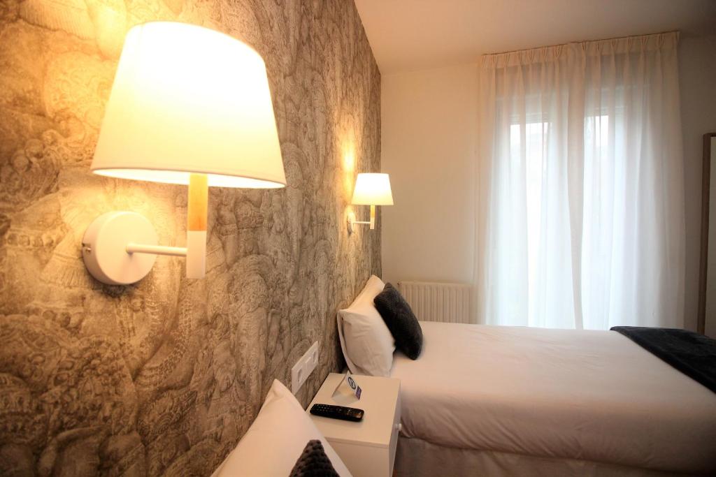 Hotel Vilagarcia في فيلاغارثيا دي أروزا: غرفة نوم بسرير ومصباح على جدار