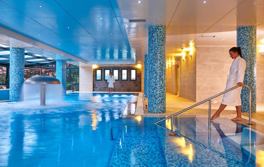 a man walking by a swimming pool in a hotel at Vasia Resort & Spa in Sisi
