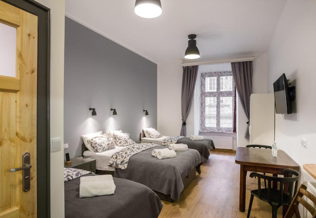 um quarto de hotel com três camas e uma secretária em Pokoje Gościnne Św. Anny em Cracóvia