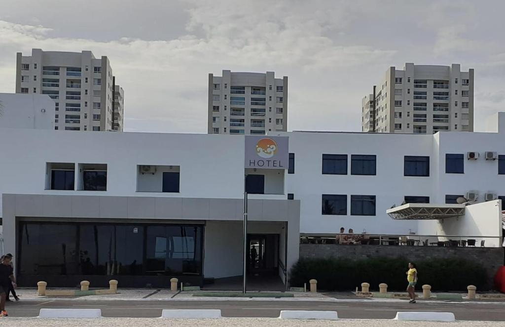Un bâtiment blanc avec des gens qui marchent devant lui dans l'établissement Hotel Algas Marinhas, à Aracaju