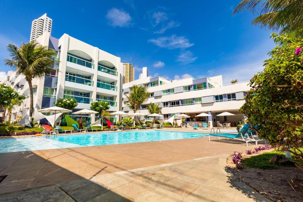 a swimming pool in front of a large building at Hotel Ponta Negra Beach Natal in Natal