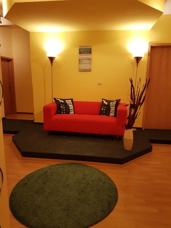 ein Wohnzimmer mit einem roten Sofa und einem grünen Teppich in der Unterkunft Scharfer Kessel in Weimar