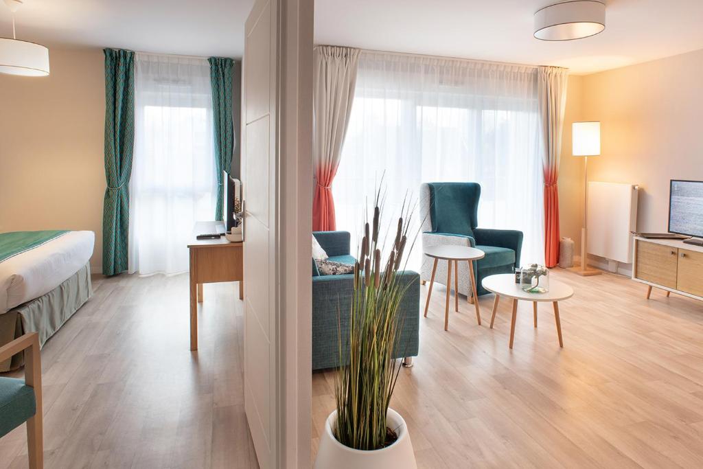 a hotel room with a bed and a living room at Résidence DOMITYS - L'Athénée in Mont-Saint-Aignan