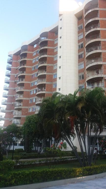 a large building with palm trees in front of it at Apartamento Mundi - Império Romano - Caldas Novas in Caldas Novas