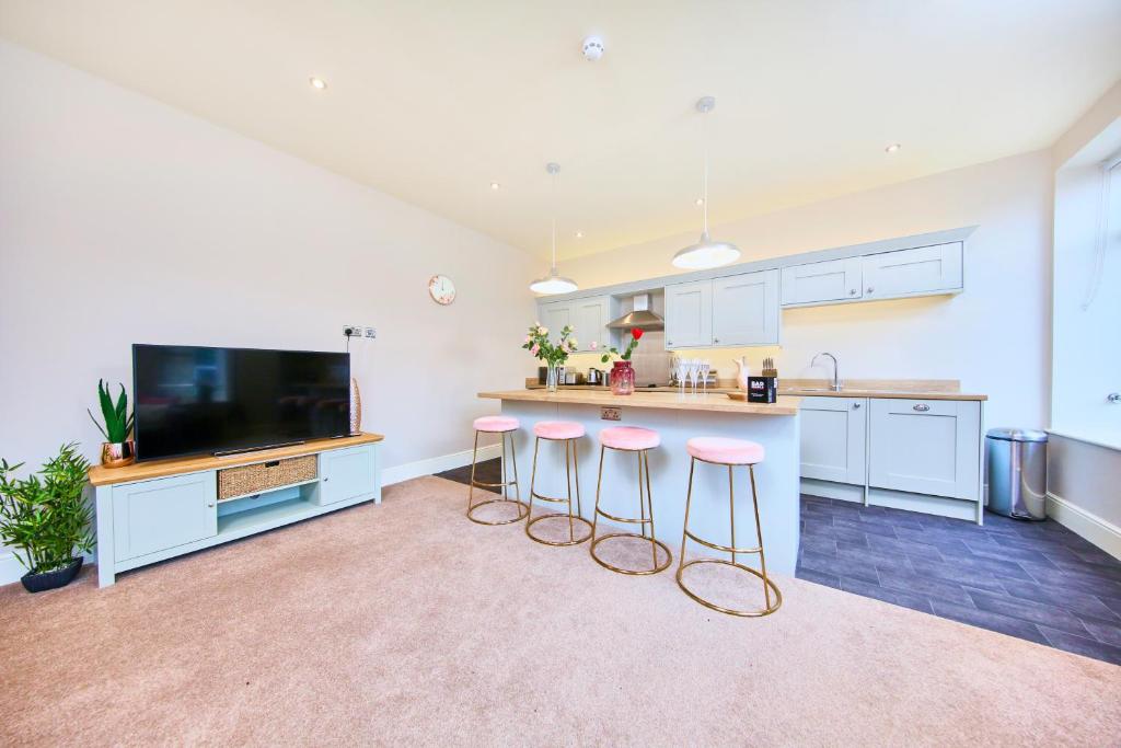 a kitchen with pink stools and a counter with a tv at The Stunning Gems of Harrogate in Harrogate