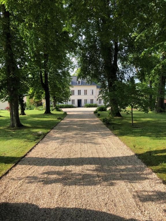 une route menant à une maison blanche avec des arbres dans l'établissement Le Clos de la Bertinière, à Bosgouet