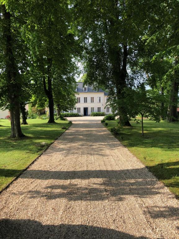 una carretera que conduce a una casa blanca con árboles en Gîte Le Clos de la Bertinière, en Bosgouet