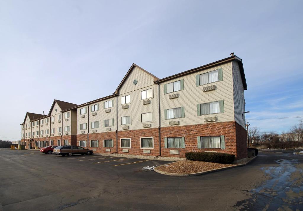 a large building with a car parked in a parking lot at Geneva Motel Inn in Saint Charles