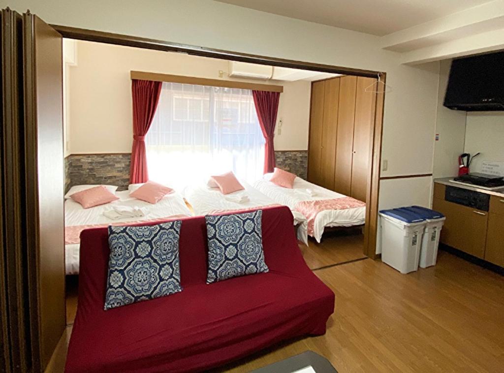 ein Wohnzimmer mit 2 Betten und einem roten Sofa in der Unterkunft Laforet Tokaichi / Vacation STAY 75082 in Hiroshima