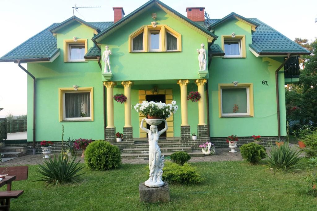 een groen huis met een standbeeld ervoor bij W zieleni in Polanica-Zdrój