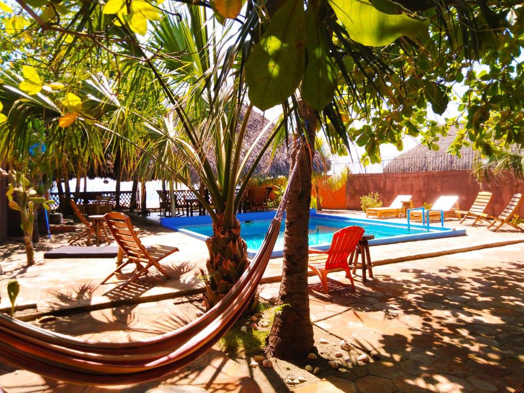 a hammock in front of a resort with a pool at El Belga Loco in Las Peñitas