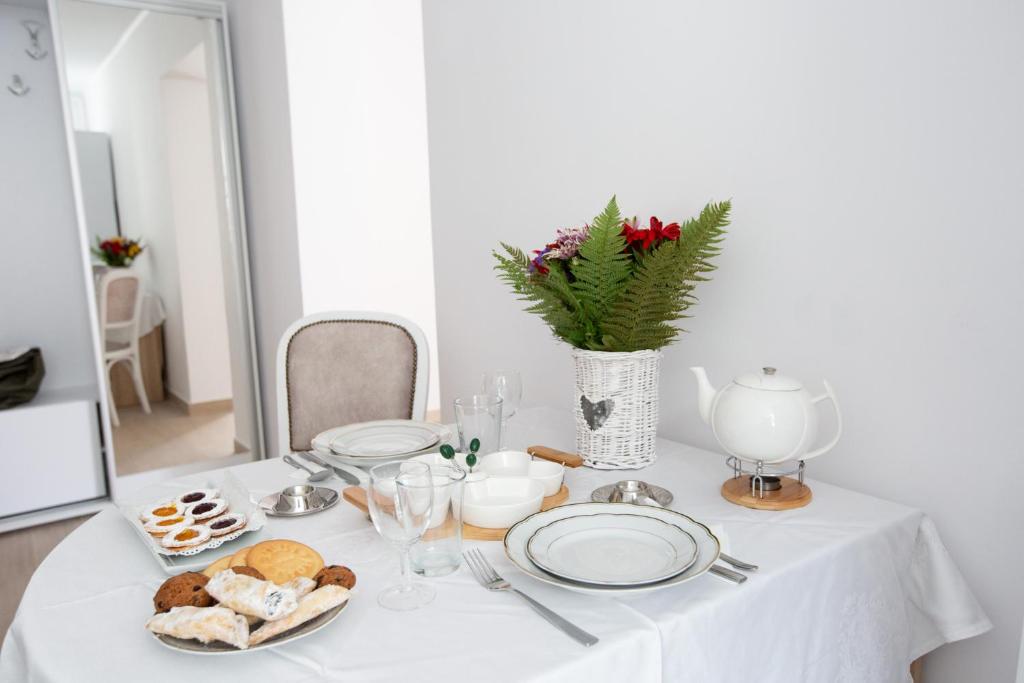a white table with plates of food on it at Perfect Apartment Central in Braşov