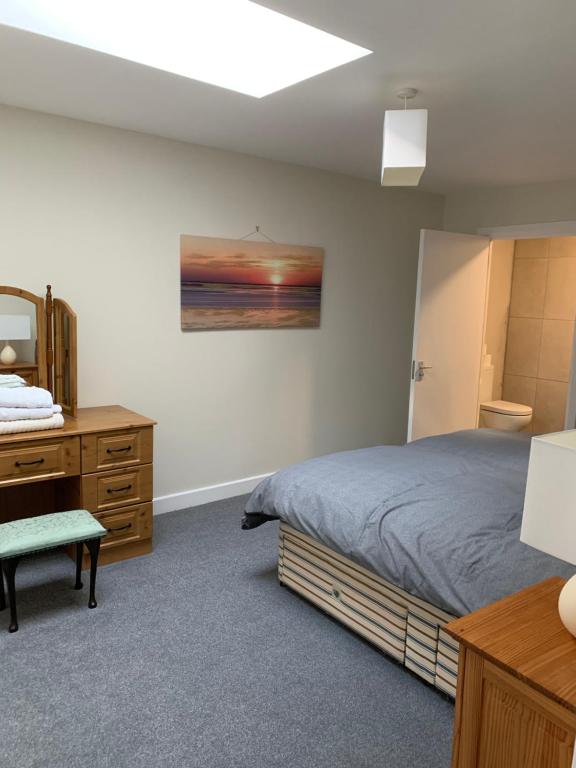 a bedroom with a bed and a dresser and a mirror at The Plaza Suites High St Bangor in Bangor