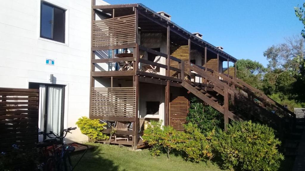 a building with wooden stairs next to a yard at Mar de Estrellas Apart Hotel in La Paloma