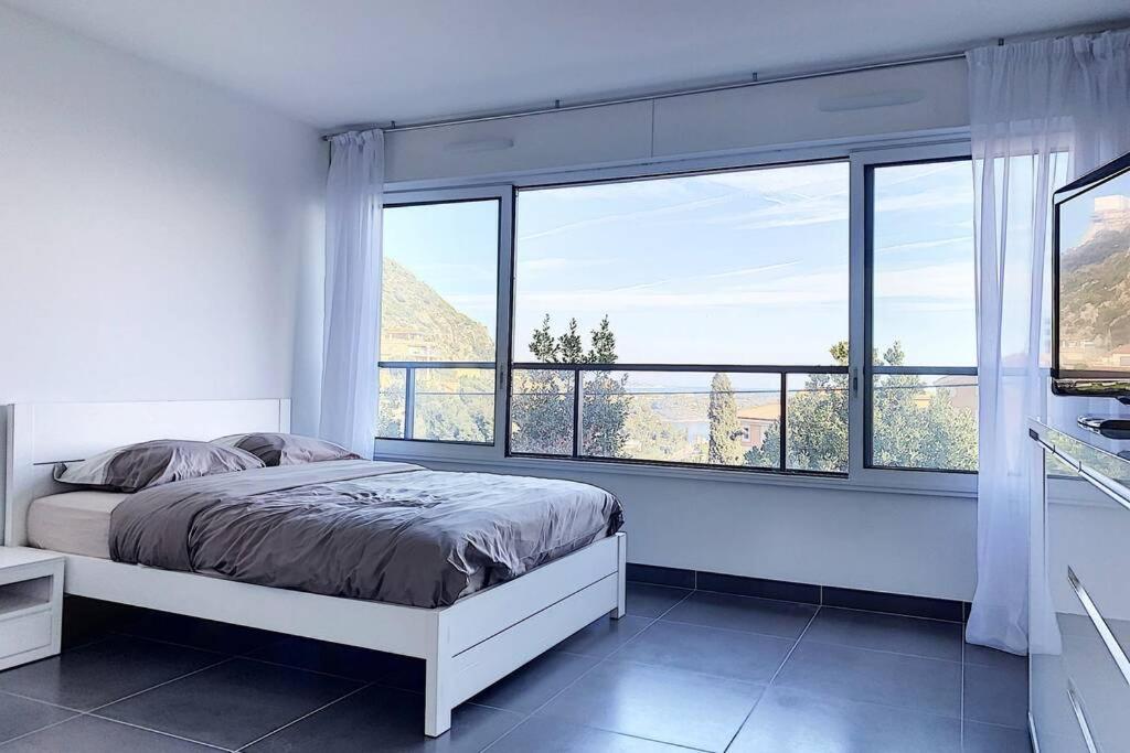 a bedroom with a bed and a large window at Great studio with a sea view and parking in 400 meters from Monaco in Beausoleil
