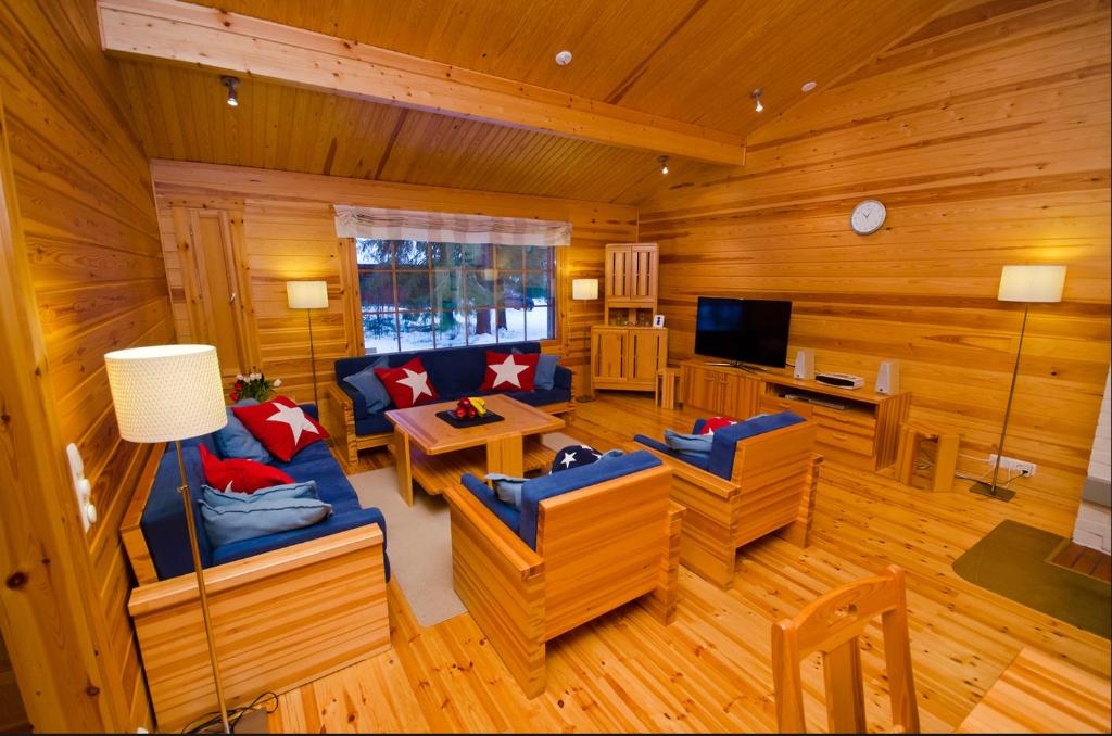 a living room with wood paneling and blue couches at Messner Tahko in Tahkovuori