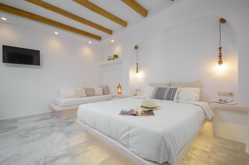 a white bedroom with a large bed and a couch at Asterias Studios in Agia Anna Naxos