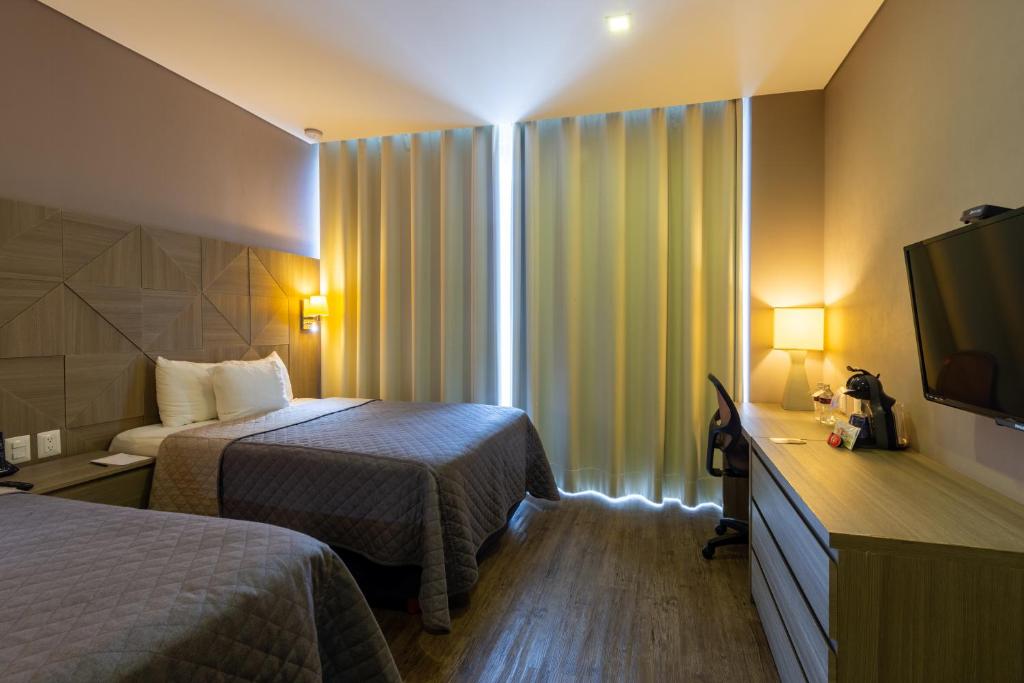 Cette chambre comprend deux lits et une télévision. dans l'établissement Hotel Glow Point - Mulza, à León