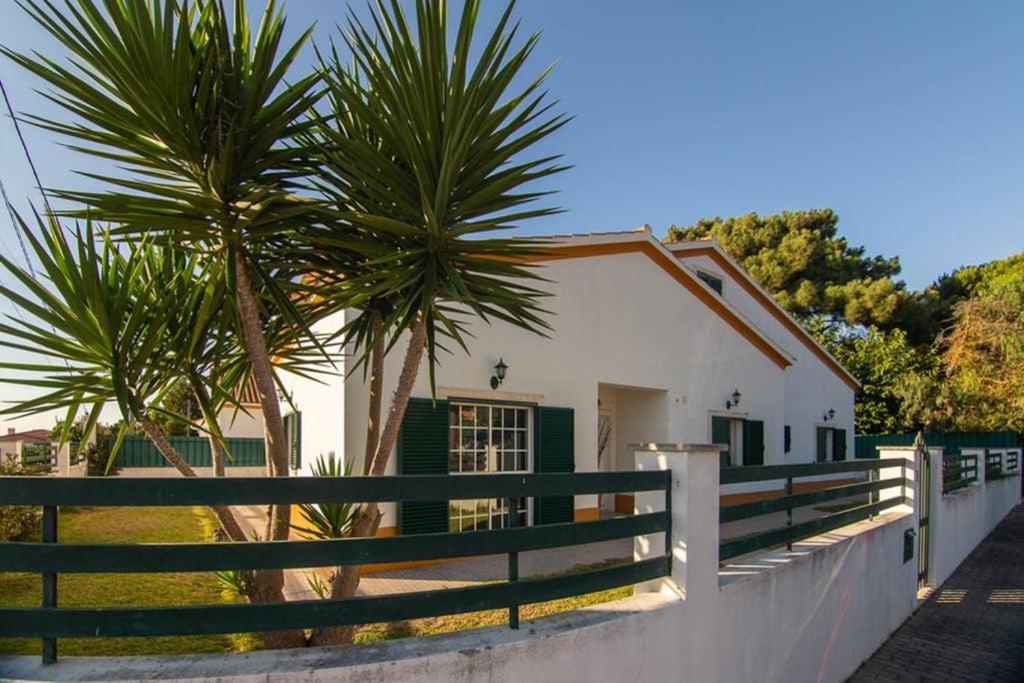 a white house with two palm trees next to a fence at The Sweet Dreams Holiday House in Azeitao