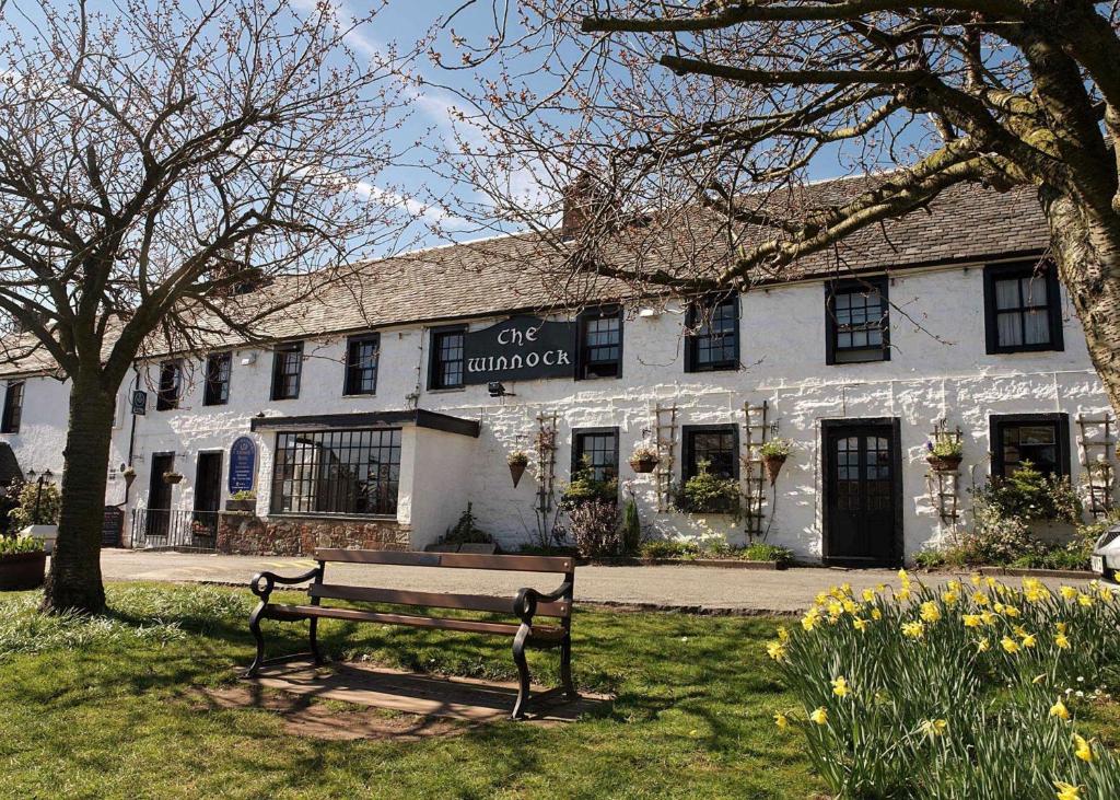 a white building with a bench in front of it at The Winnock Hotel in Drymen