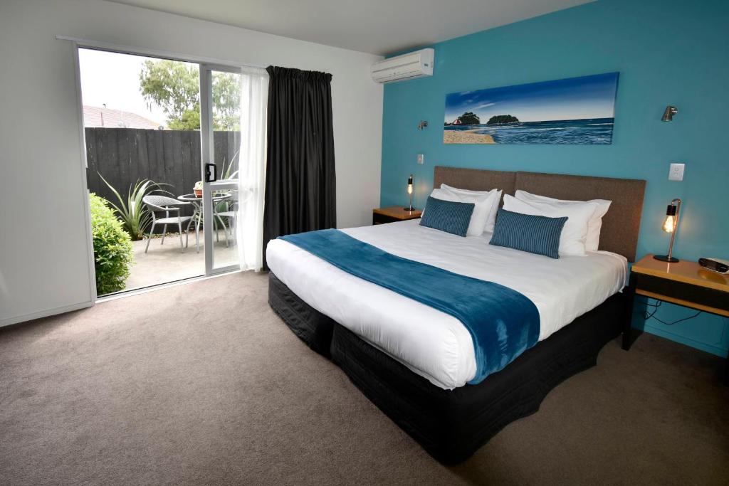 a bedroom with a large bed with blue walls at FYFFE on Riccarton in Christchurch