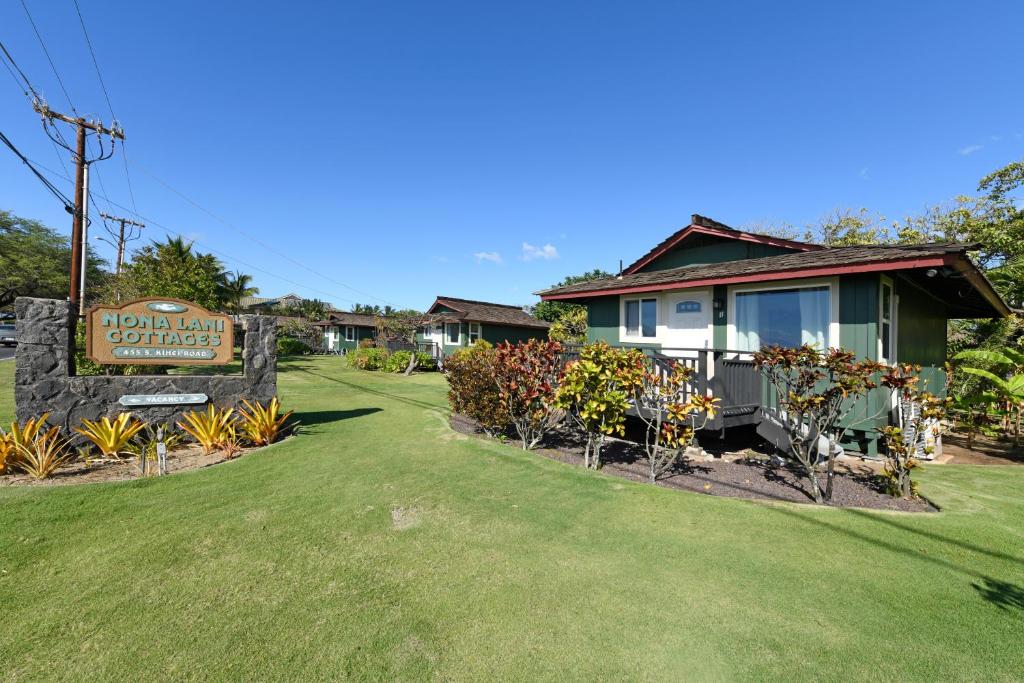 a house with a sign in front of a yard at Nona Lani Cottages in Kihei
