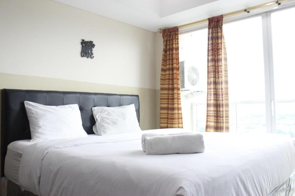 Modern Studio Room at Tamansari La Grande Apartment By Travelio في باندونغ: سرير مع ملاءات ووسائد بيضاء في غرفة النوم