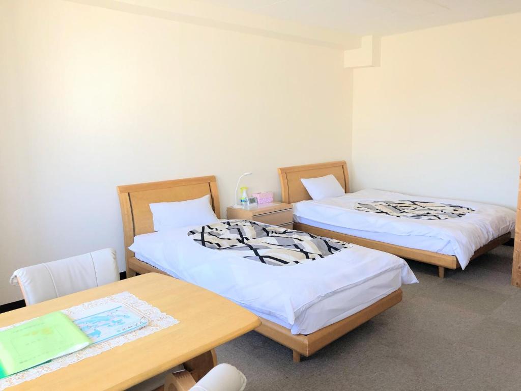two beds in a room with a table and chairs at Weekly Mansion Ise No.6 in Ise