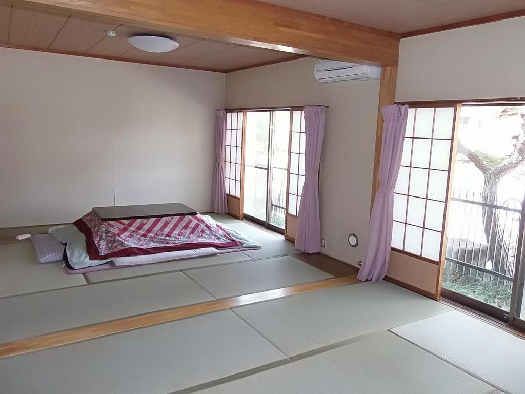 a bedroom with a bed in a room with windows at 布引観音温泉 in Ōhinata