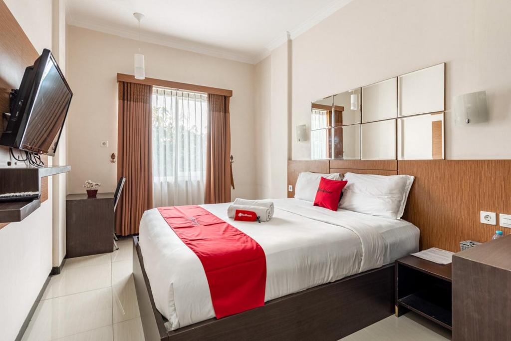 a hotel room with a large bed with red pillows at RedDoorz Syariah @ Soekarno Hatta Indah 2 in Blimbing