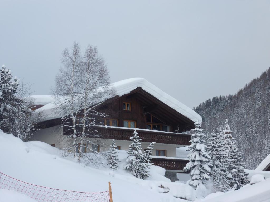 ein schneebedecktes Gebäude mit einem Zaun in der Unterkunft Patschei Trid in Samnaun