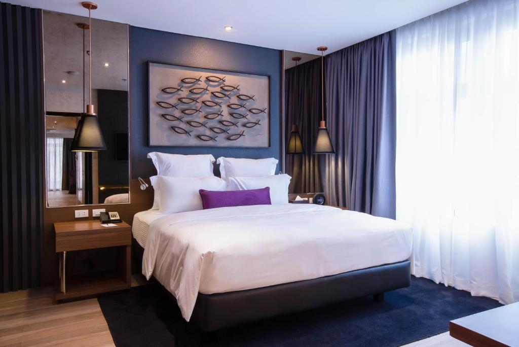 a bedroom with a large white bed with purple pillows at Coro Hotel in Manila