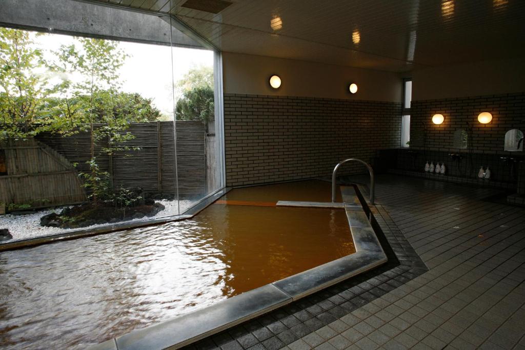 a bath tub filled with water in a building at Granvillage Toya Daiwa Ryokan Annex in Lake Toya