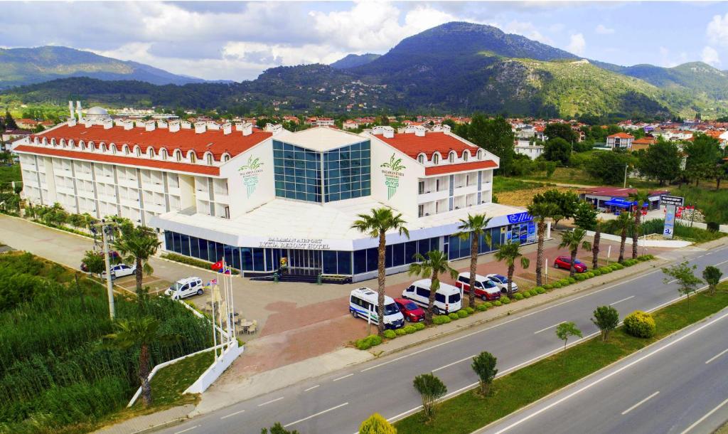 un grand bâtiment blanc avec un toit rouge à côté d'une rue dans l'établissement Dalaman Airport Lykia Thermal & Spa Hotel, à Dalaman