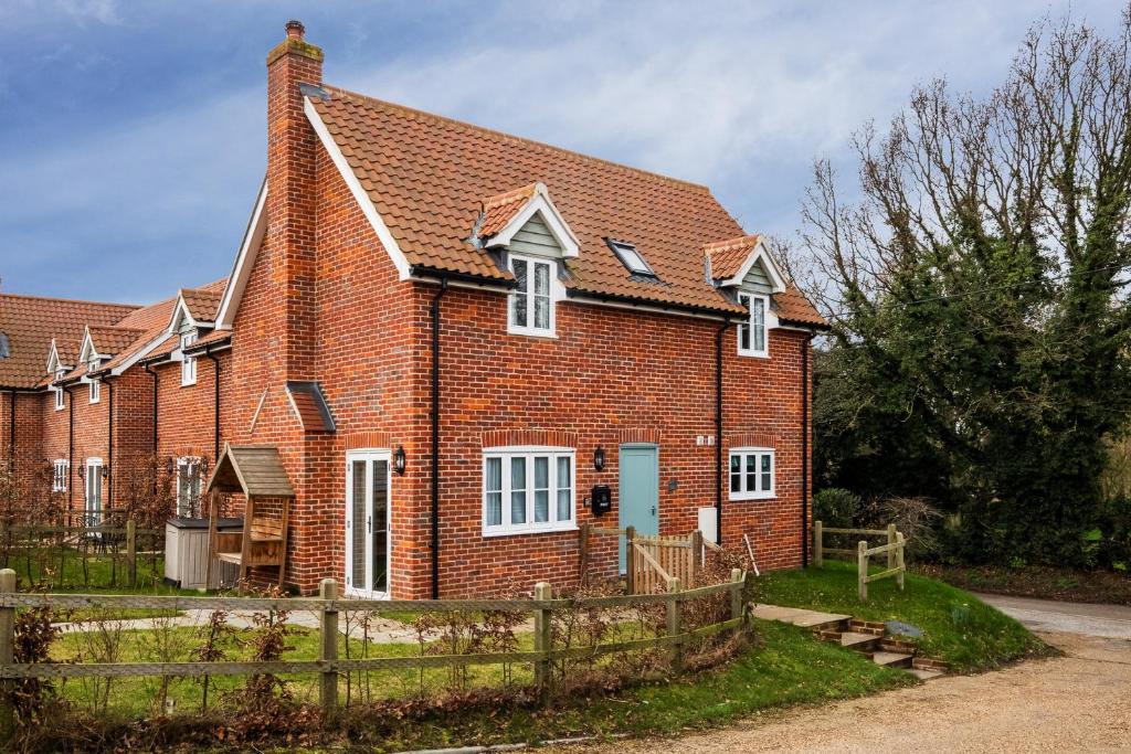 a red brick house with a fence in front of it at 1 Roseanna Cottage, Middleton - Aldeburgh Coastal Cottages in Middleton