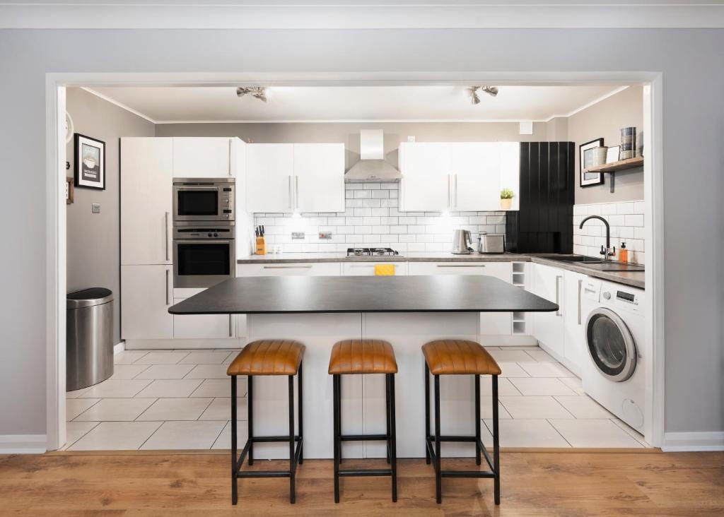 a kitchen with white cabinets and a black island with stools at Burlington Street with free parking Nr Brighton College and Hospital in Brighton & Hove
