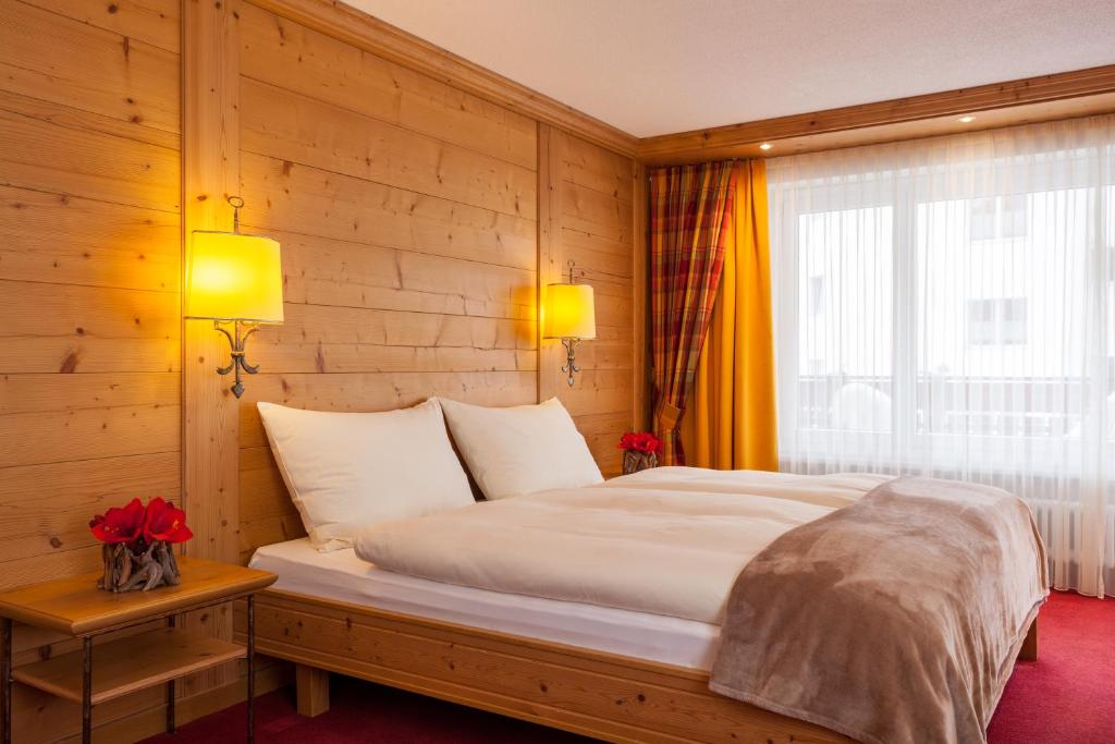 Un dormitorio con una cama grande y una ventana en Hotel Holiday, en Zermatt