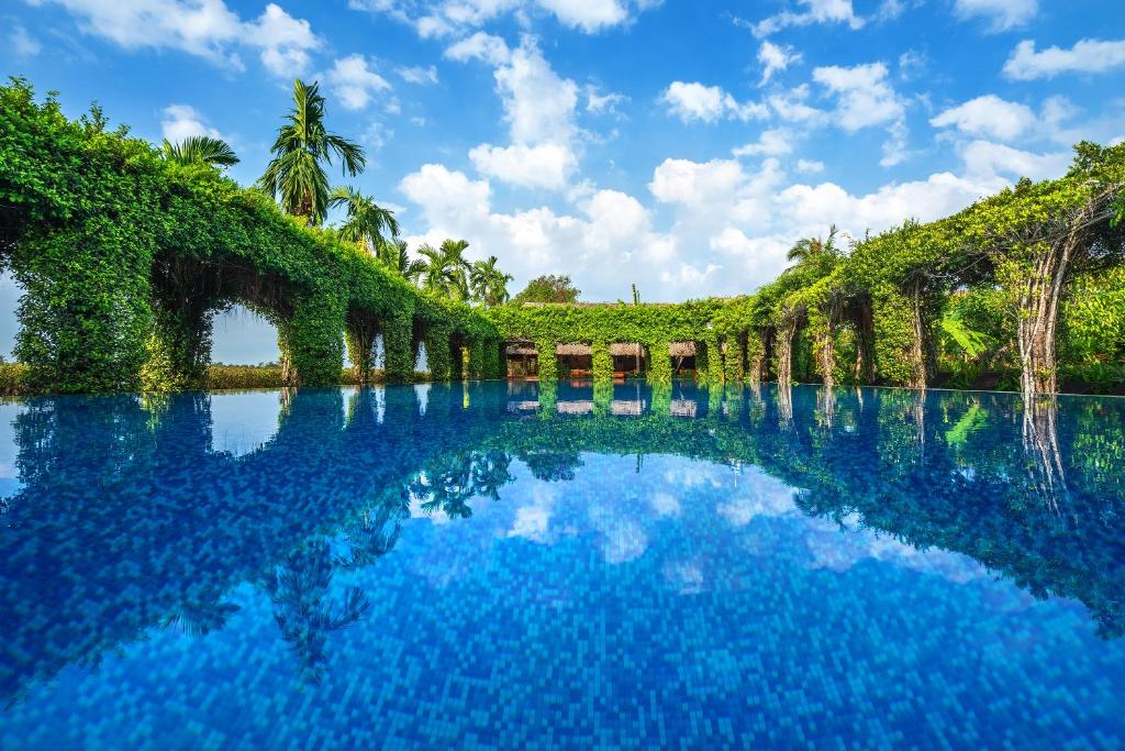 una piscina de agua con árboles y un puente en Mekong Lodge Resort en Cai Be