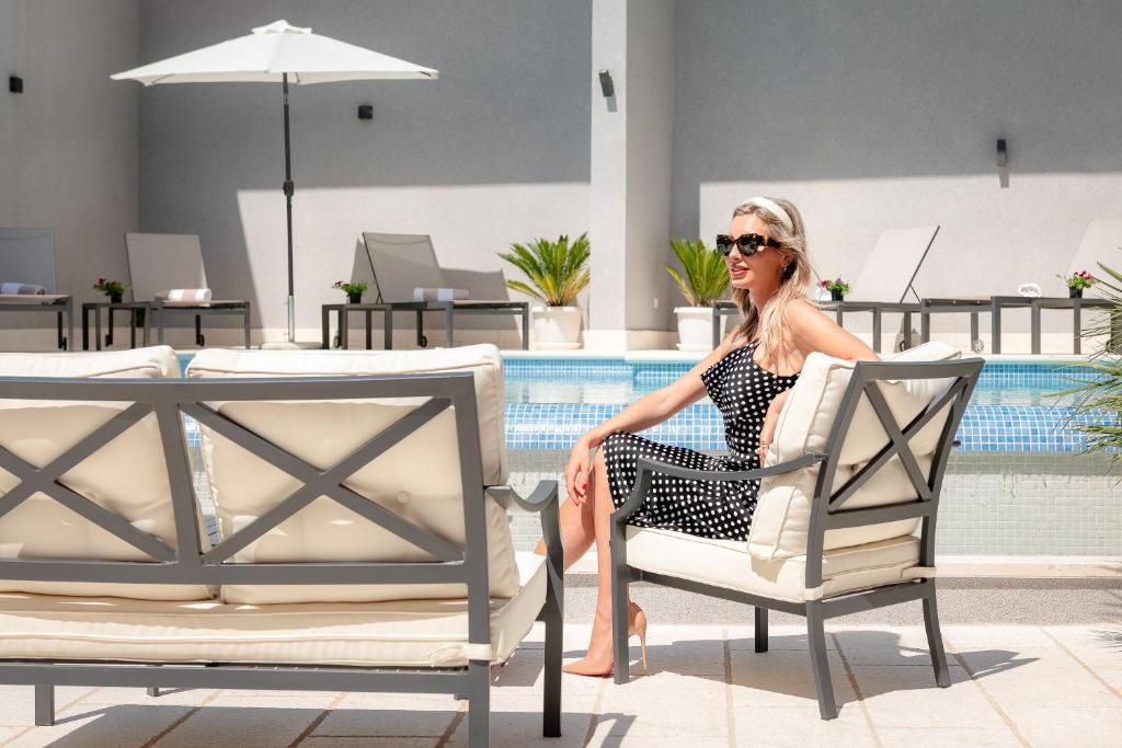 a woman sitting in a chair next to a pool at Hotel Cvita in Split